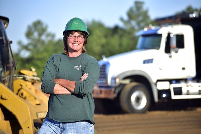 A female road construction worker smiles on site of a Georgia highway construction project