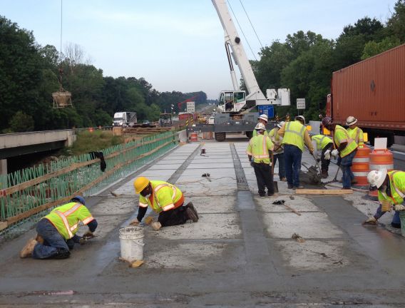 A highway construction crew works diligently to smooth out concrete on a project they are working on