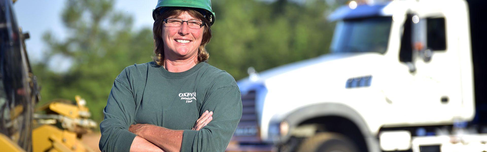 A female road construction worker smiles next to her truck that she drives with her cdl license she uses in Georgia