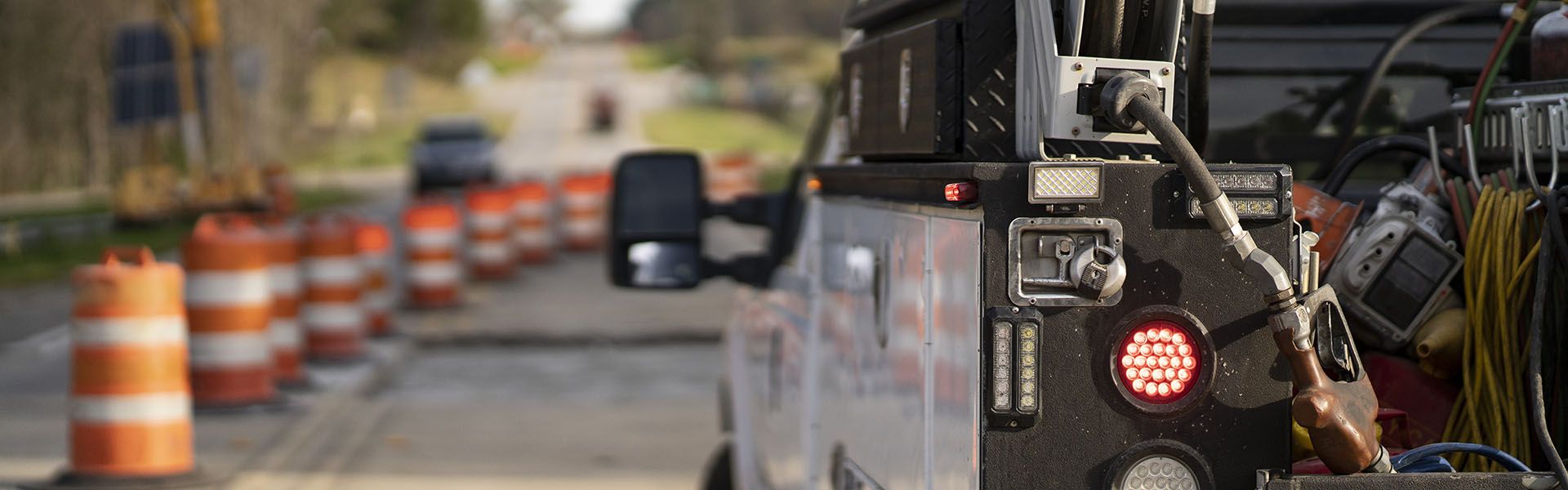 This work truck is driven by a Georgia road job worker. As they drive, they pass by orange construction cones.