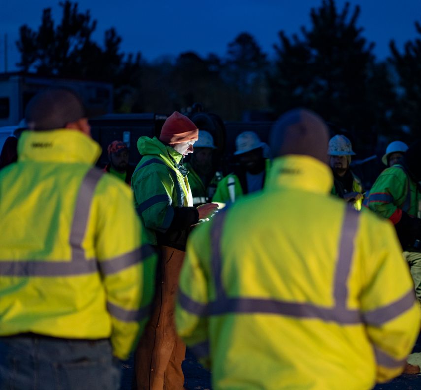 A team of highway construction workers in Georgia huddles around before their day begins and they head out to job sites
