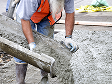 A concrete laborer helps pours concrete during a typical day of his road construction career