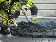 Two asphalt paving workers who are shoveling as a part of their road construction career in Georgia