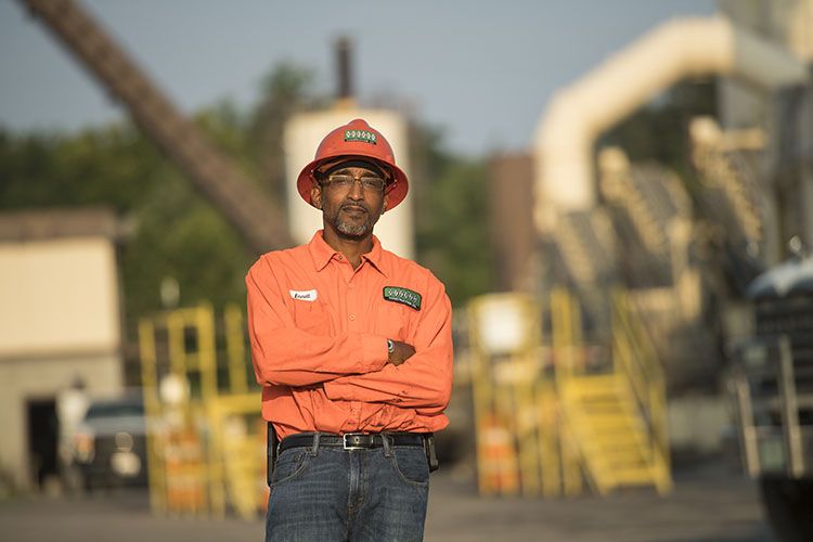 A road construction worker wearing an orange hard hat stands on site of his road job in Georgia