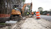 A highway construction crew  uses tools including a crane on the side of the road to expand the road in Georgia