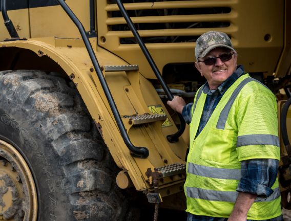 A man with a CDL license smiles before he climbs into his heavy equipment vehicle 