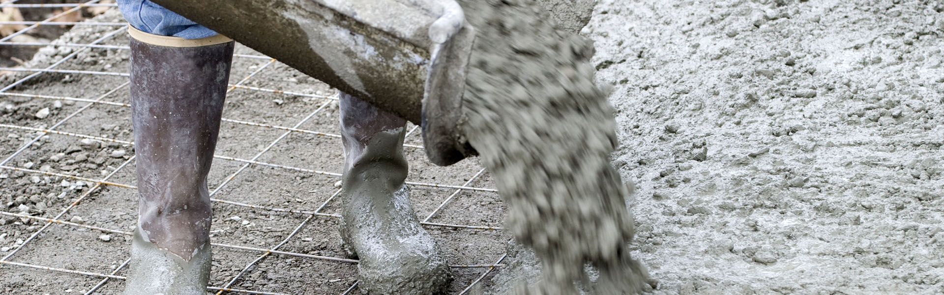 A concrete laborer pouring concrete on site on his highway construction job