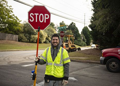 A young construction worker holds a stop sign on site of his highway construction in Georgia