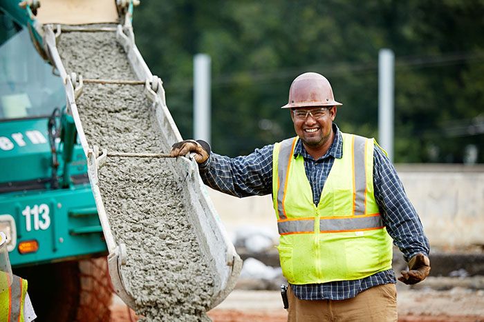 Luis Cervantes, a highway construction worker in Georgia, smiles while pouring concrete on site.