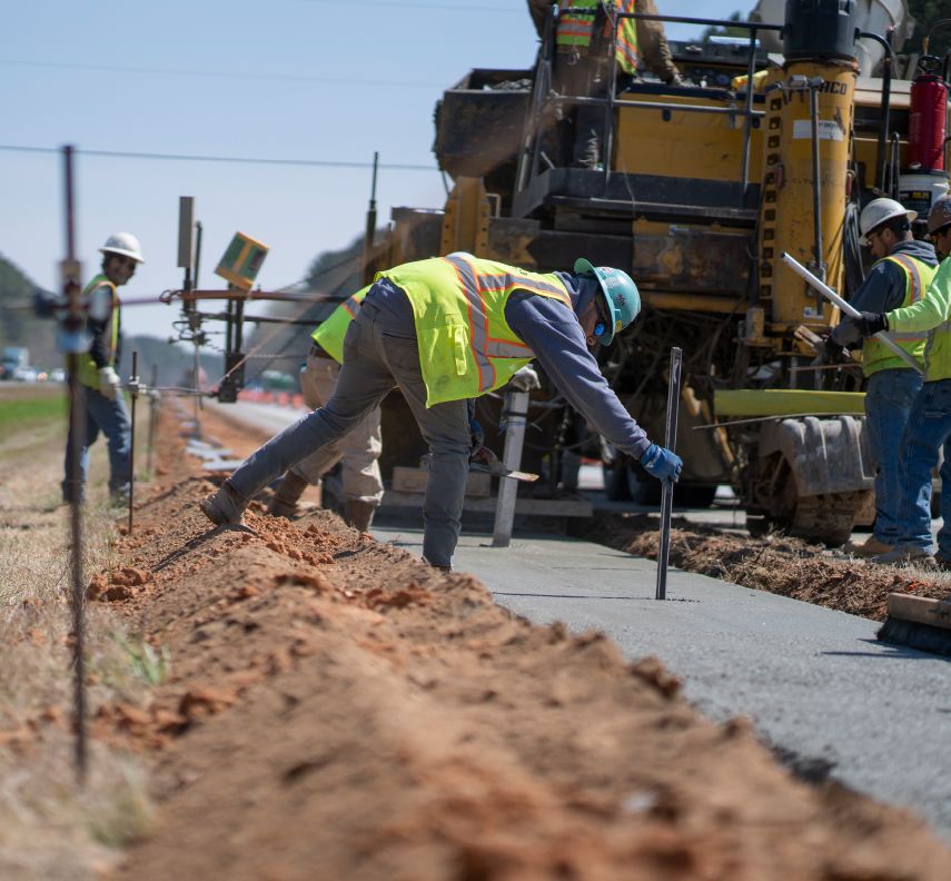 A highway construction career puts metal rods into newly poured concrete on site of their Georgia construction project
