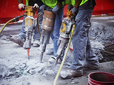 Three highway construction workers in Georgia drill up old pavement before they begin to pave new roads.