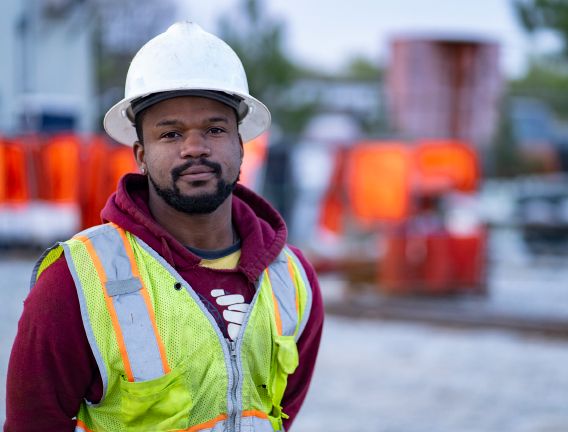 A young asphalt paving worker smiles on site of his road construction career in Georgia