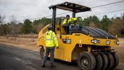 A highway construction worker operating a piece fo heavy equipment machinery in Georgia speaks to a fellow worker