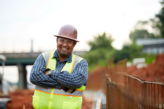 Luis Cervantes smiles and crosses his arms on site of his road construction job site in Georgia.