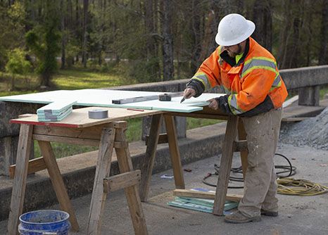A bridge carpenter studies blueprint of bridge he is building during his highway construction career in Georgia