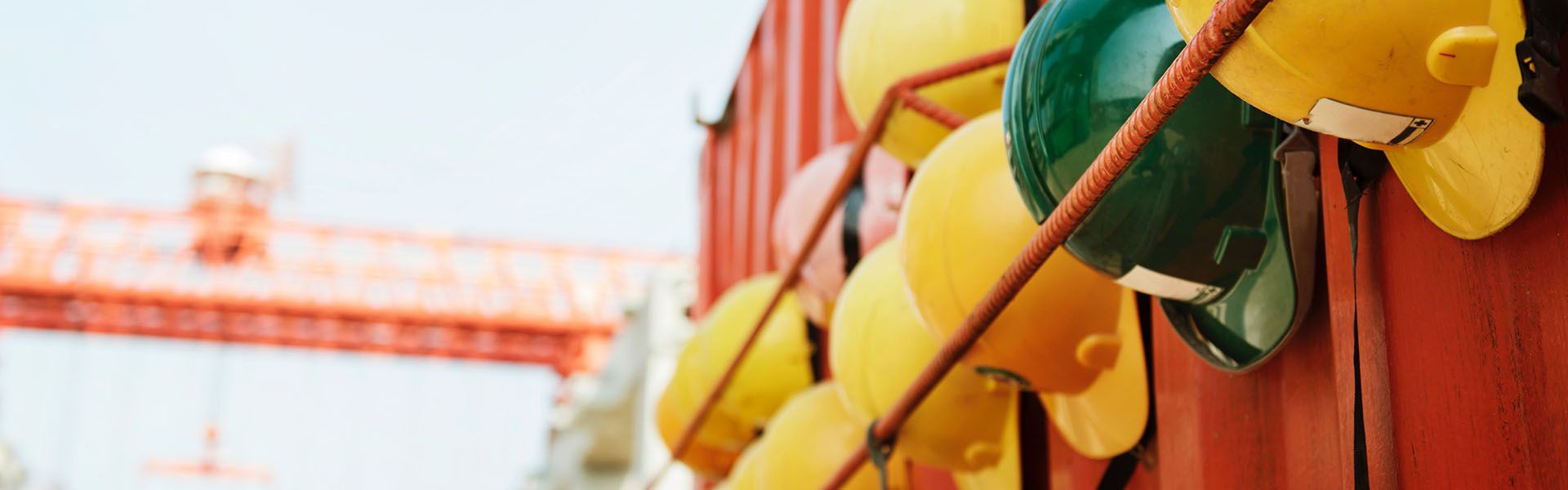 A row of yellow and green construction hats leaning against the side of an orange wall. Road construction workers in Georgia wears these.