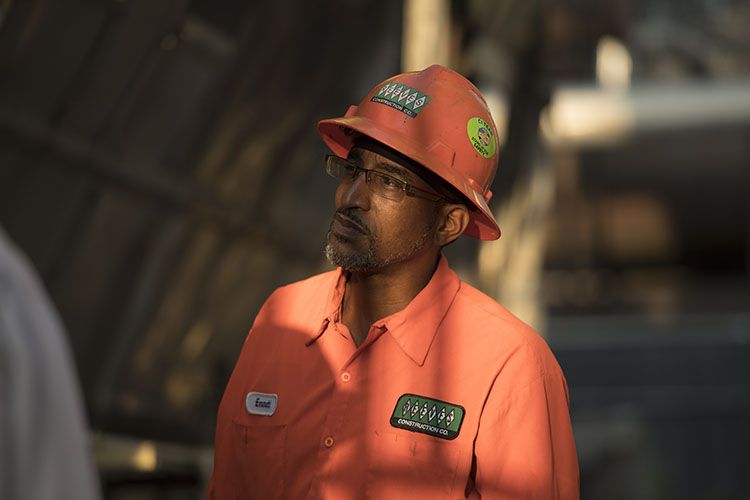 Road construction worker in Georgia wearing a hat listens to his heavy equipment operator about what needs to do be done.