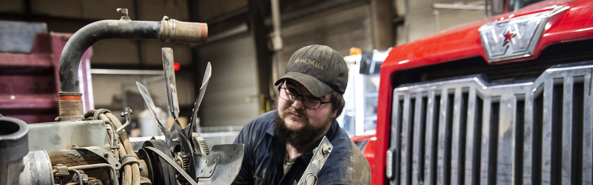 A heavy equipment mechanic smiles while wearing a green hard hat on site of his road construction career in Georgia