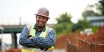 Luis Cervantes smiles and crosses his arms on site of his road construction job site in Georgia.